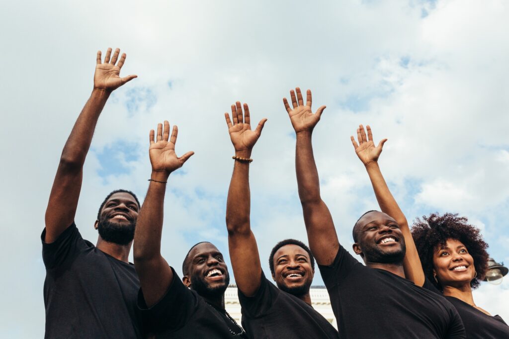 Hand of happy black people against a blue sky